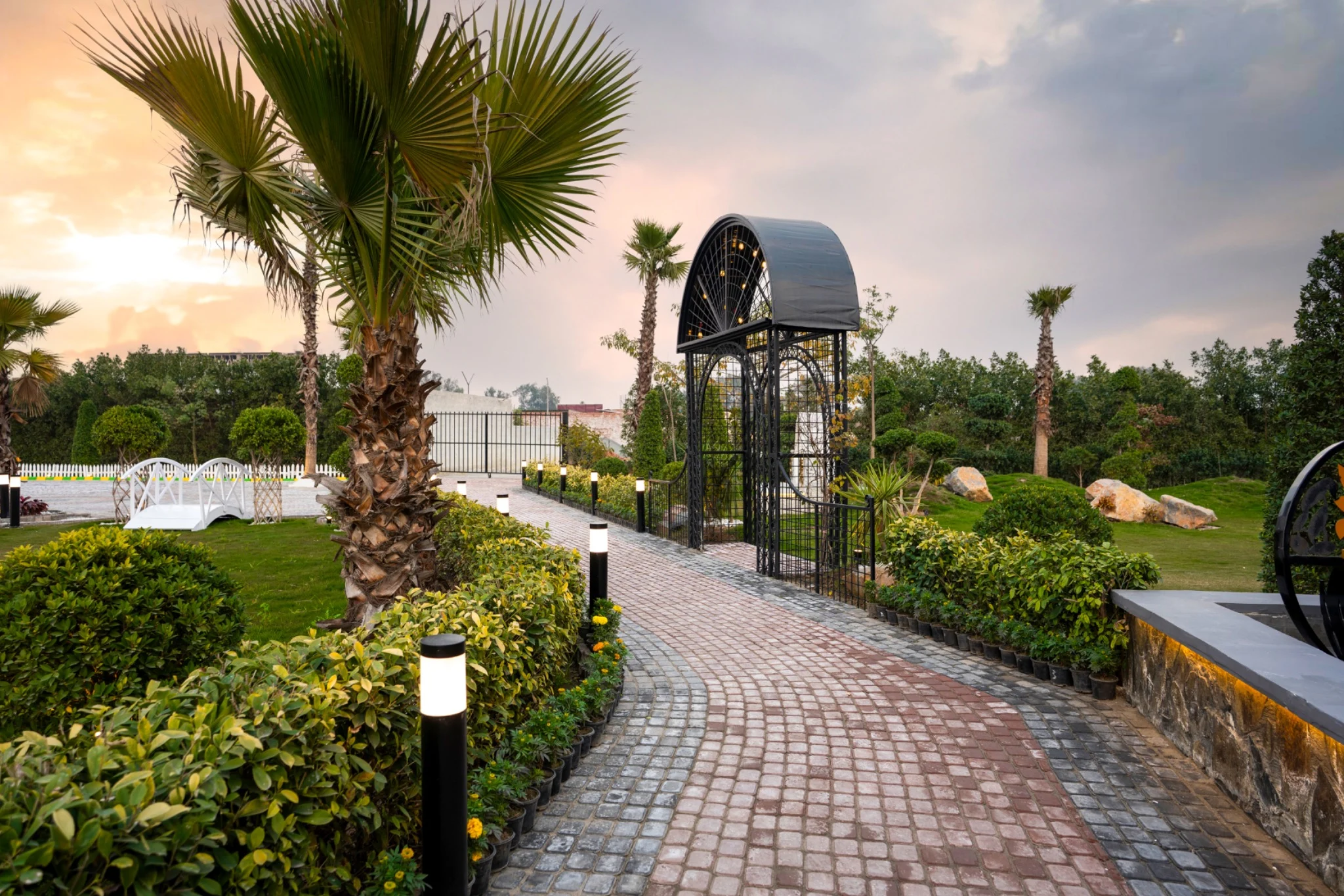 A palm-lined garden path leading through the sculptural entrance