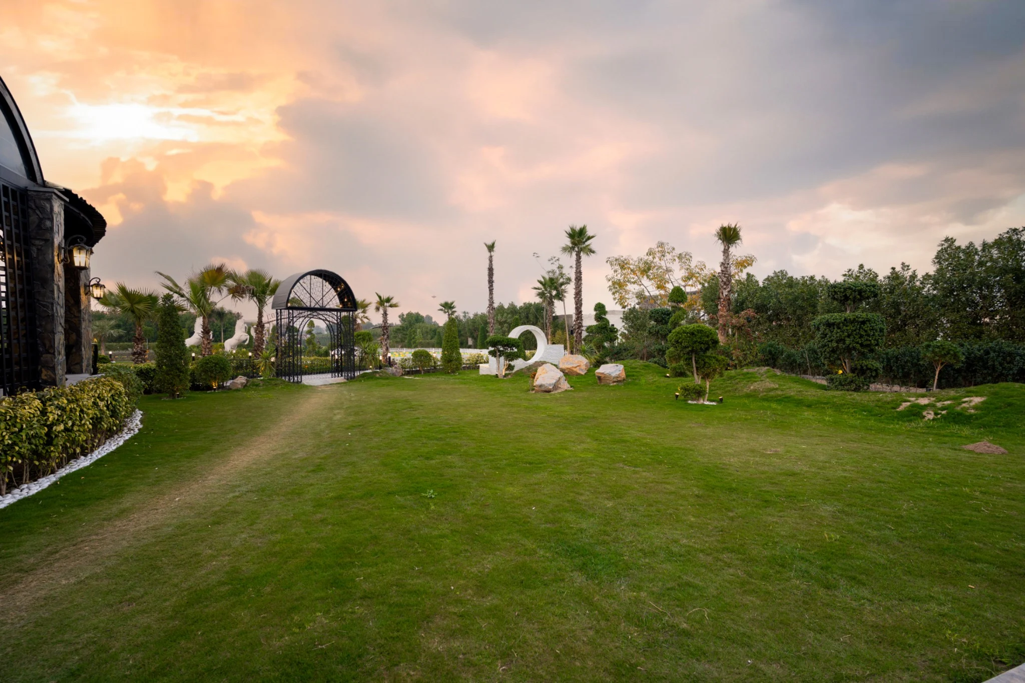 The open garden with palms, lawns and sculptural details at sunset