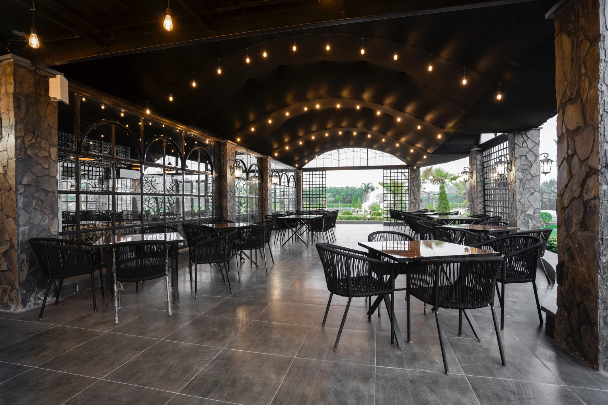 Warm pendant lights and timber tables inside a garden-facing pavilion